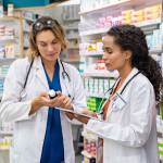 Two multiethnic pharmacists checking inventory at hospital pharmacy.