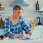 Elderly retired person working from home, telecommuting using remote internet job online communication on modern