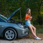Young woman near broken car speaking by phone needs assistance.