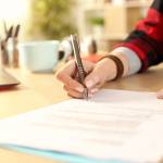 A closeup of a woman's hand signing a contract