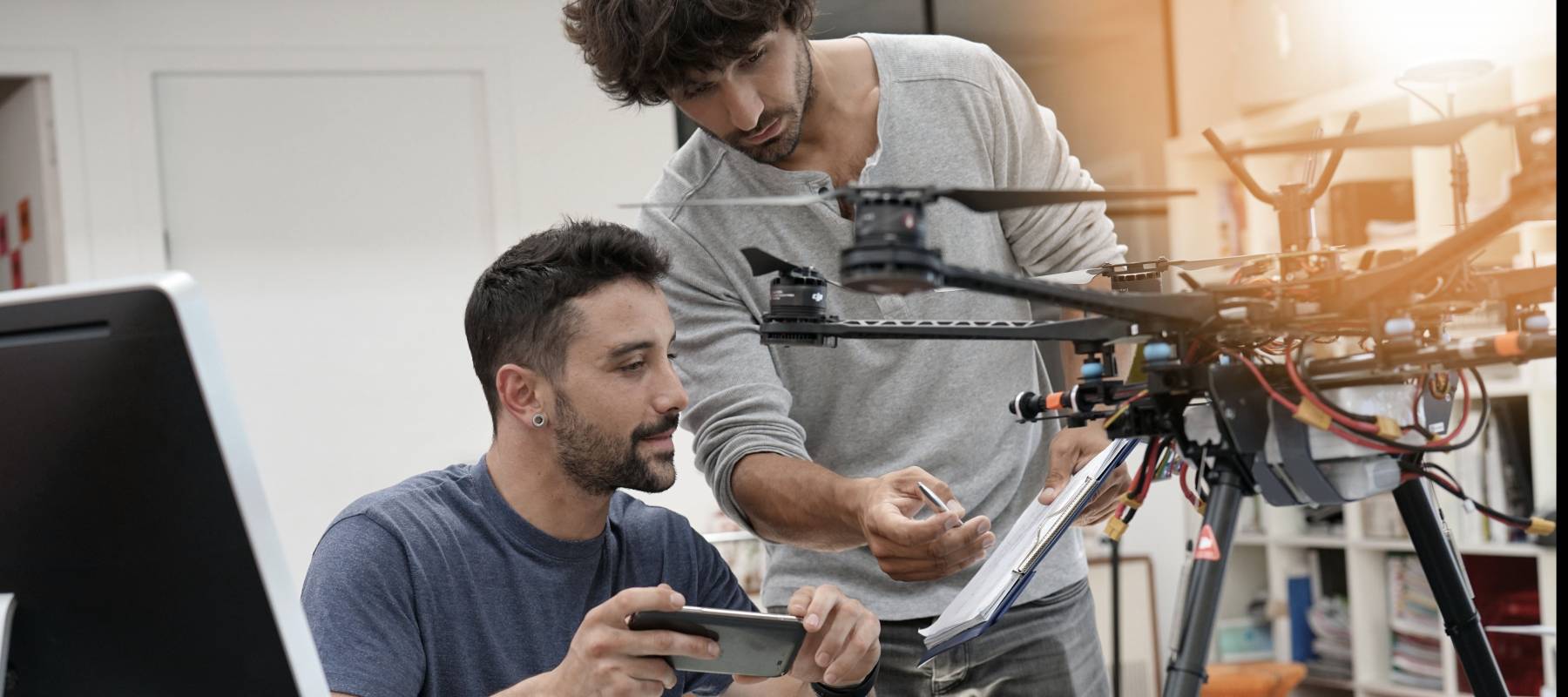 Engineer and technician working together on drone in office.