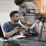 Engineer and technician working together on drone in office.