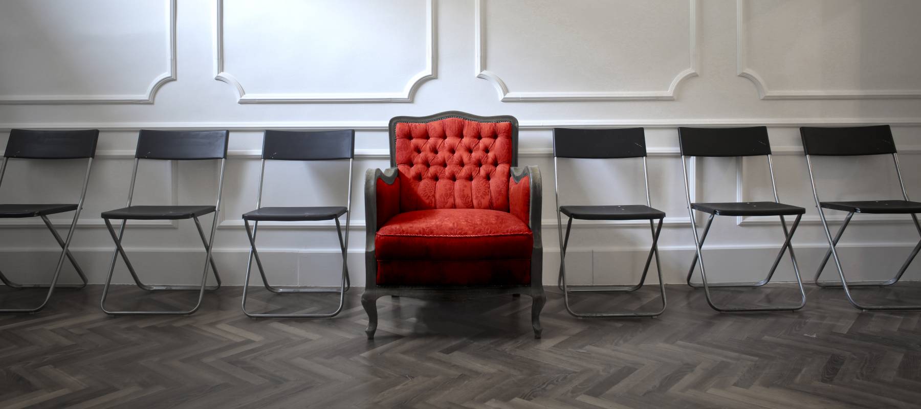 Red VIP chair in the centre of basic folding chairs, wealth concept