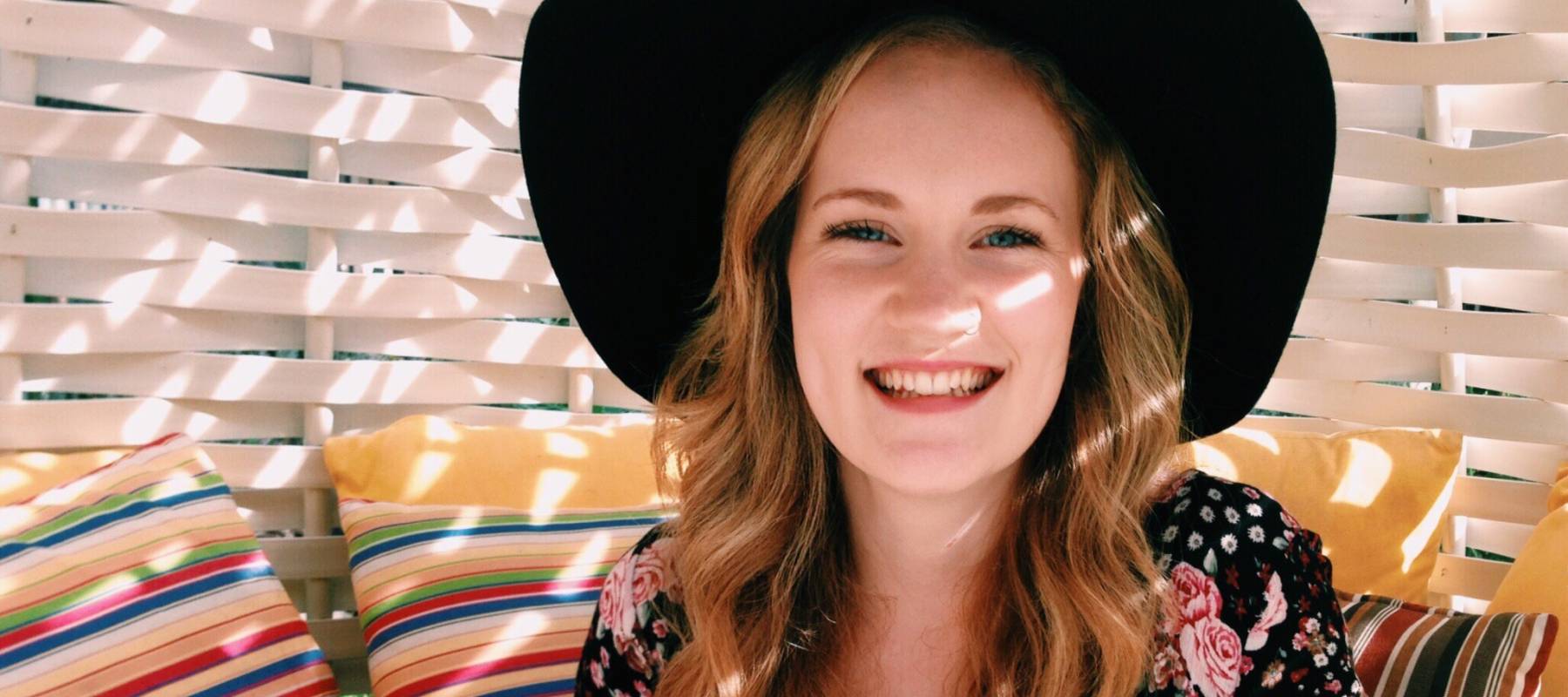 Young woman smiling and holding coffee.
