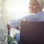 Portrait of smiling senior woman senior woman sitting on wheelchair at home