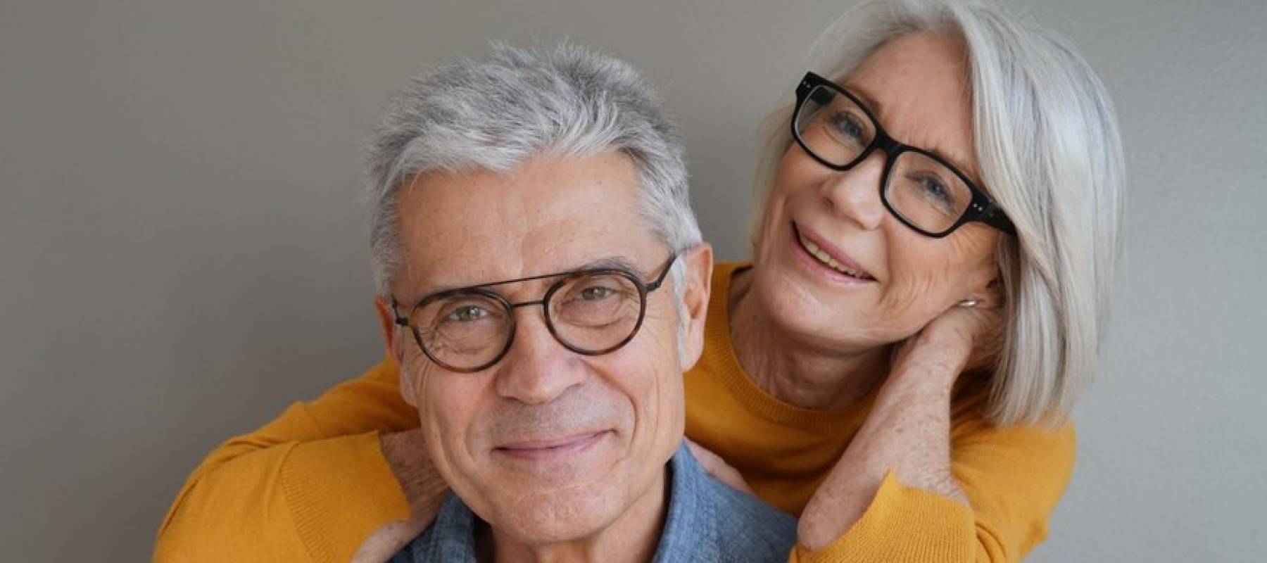 Portrait of relaxed fun senior couple wearing glasses on background