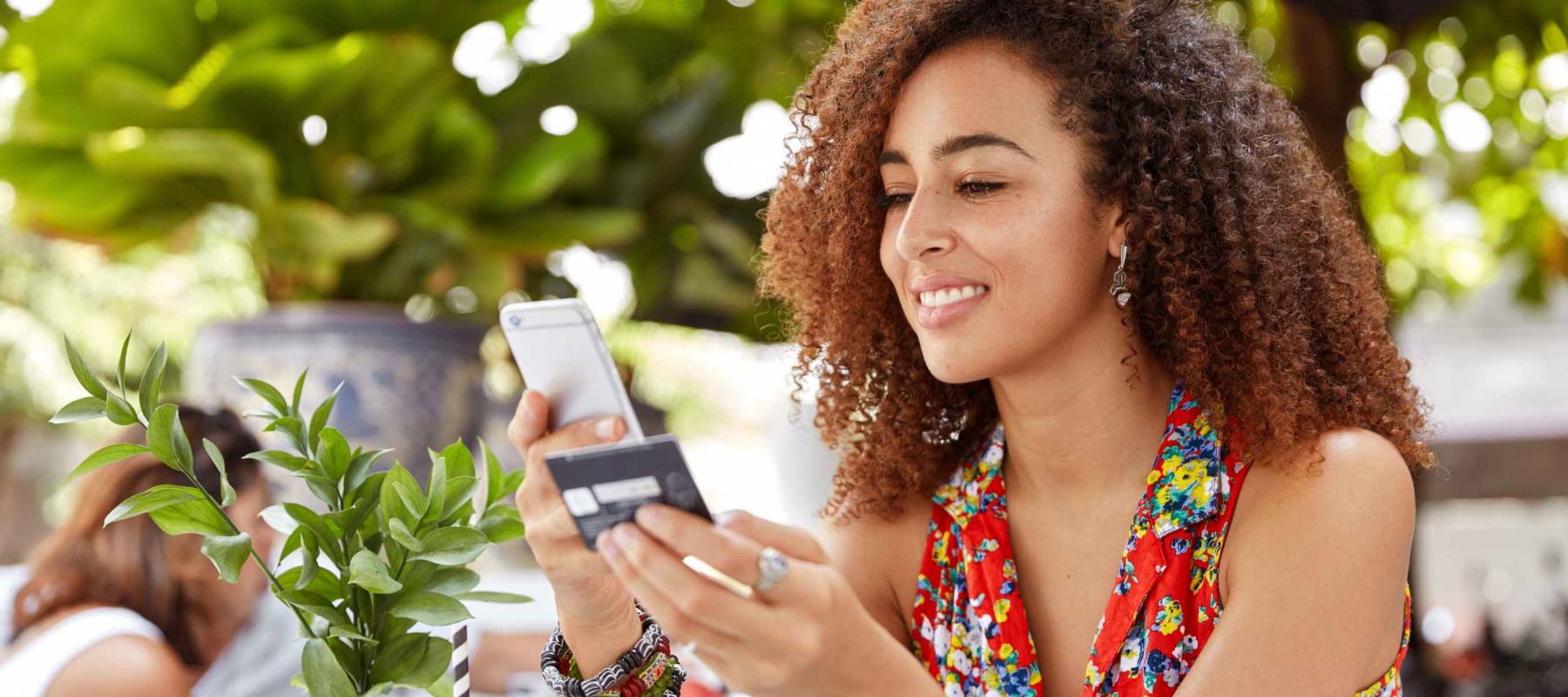 A young woman buying something on her phone while holding her credit card