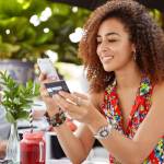 A young woman buying something on her phone while holding her credit card