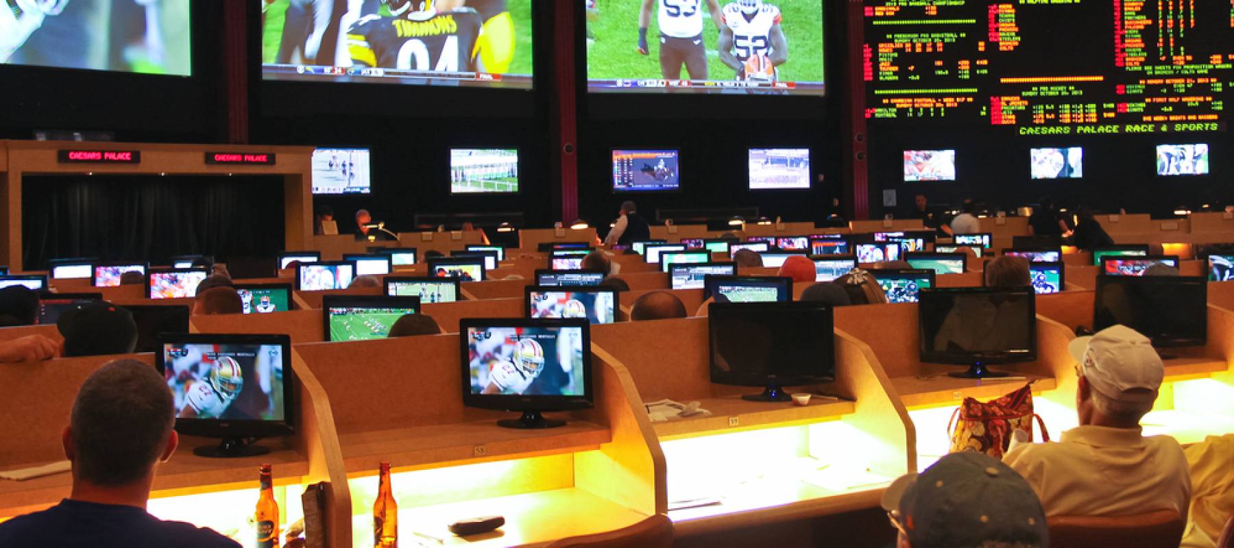 Two men sitting in front of a room of screens taking part in sports betting in Las Vegas.
