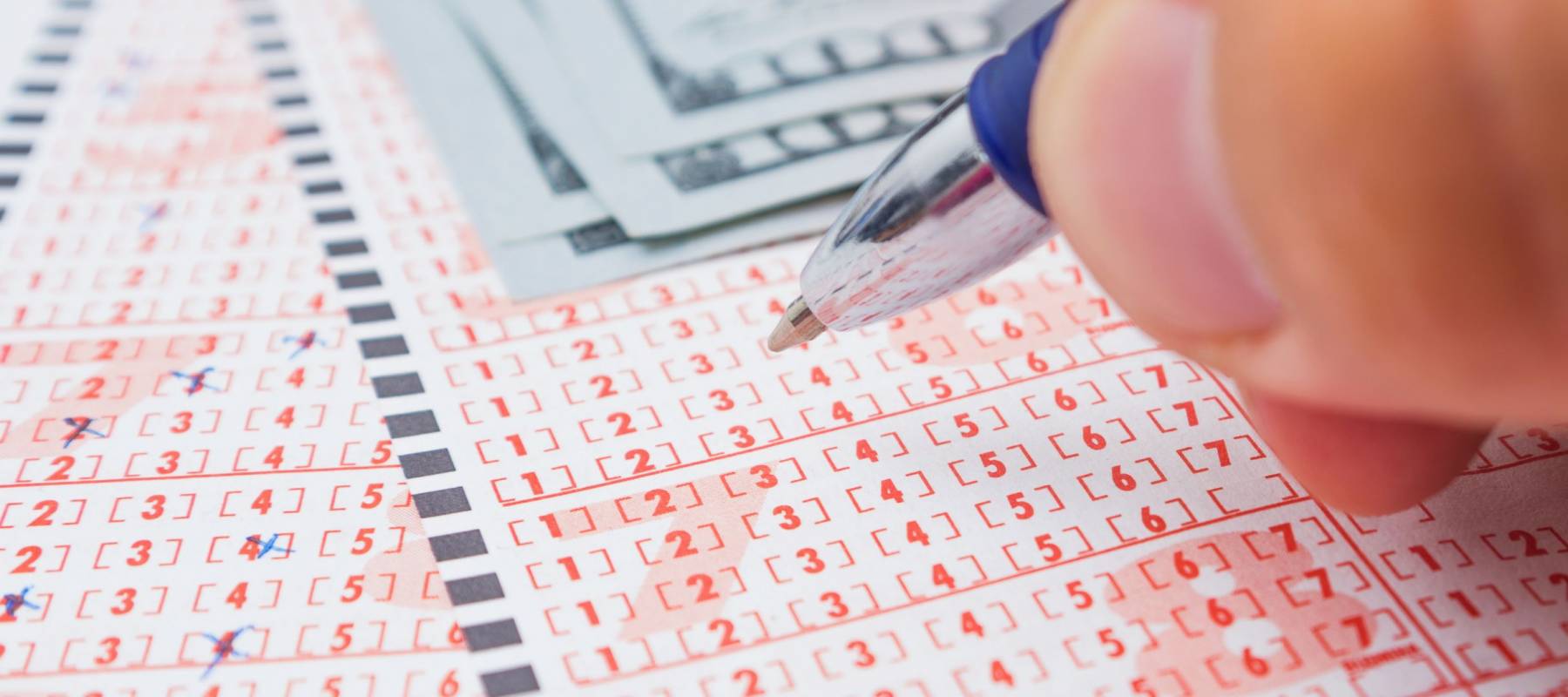 Male's hand marking number on lottery ticket. Close-up, selective focus.