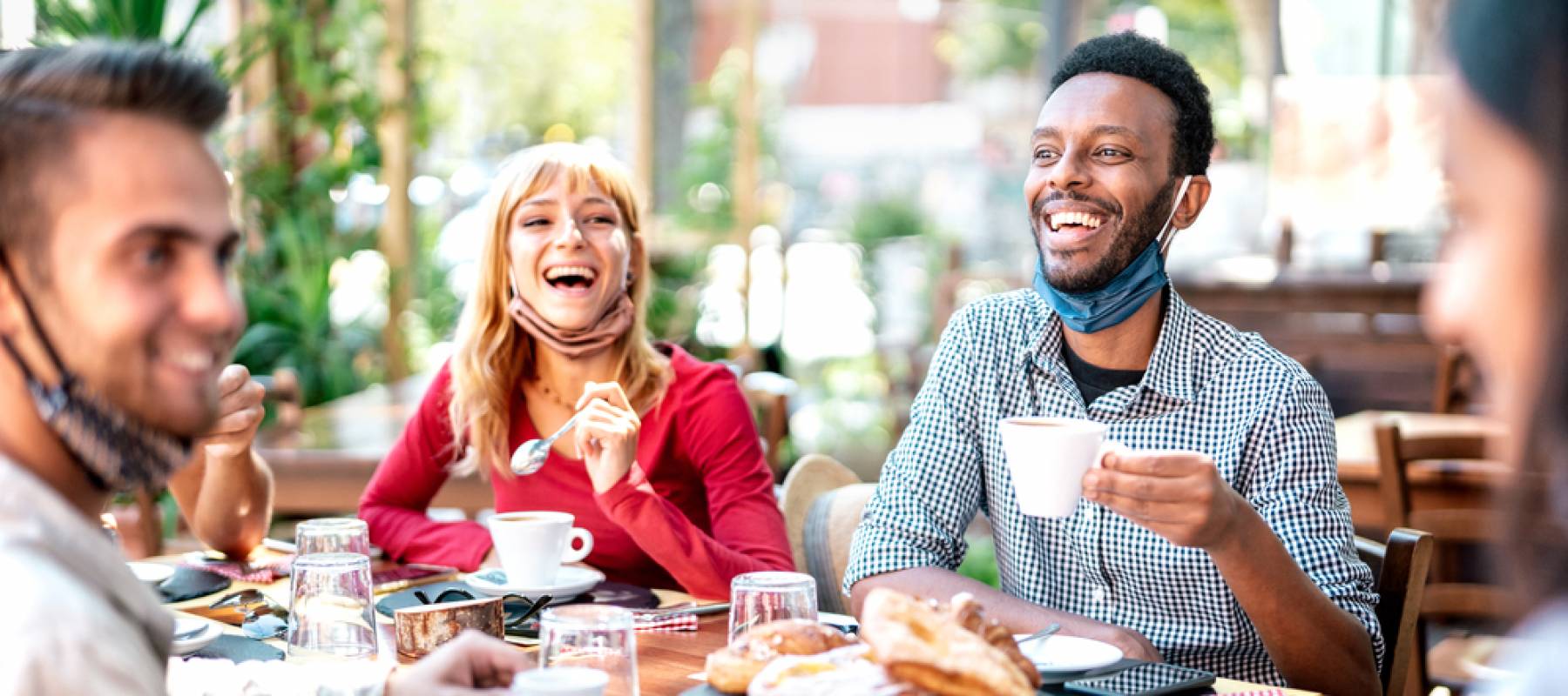 Group of young people sit around a table at a restaurant, laughing and chatting.