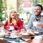 Group of young people sit around a table at a restaurant, laughing and chatting.