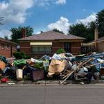 Pile of belongings outside of a run-down looking house.