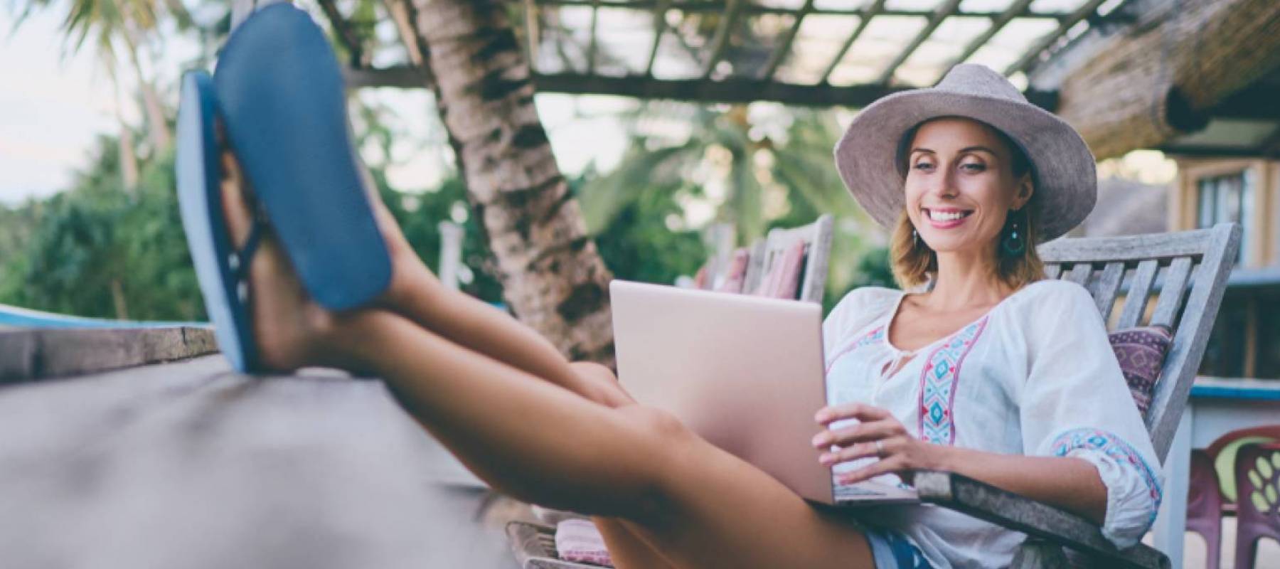 Young woman using laptop in cafe on tropical beach.