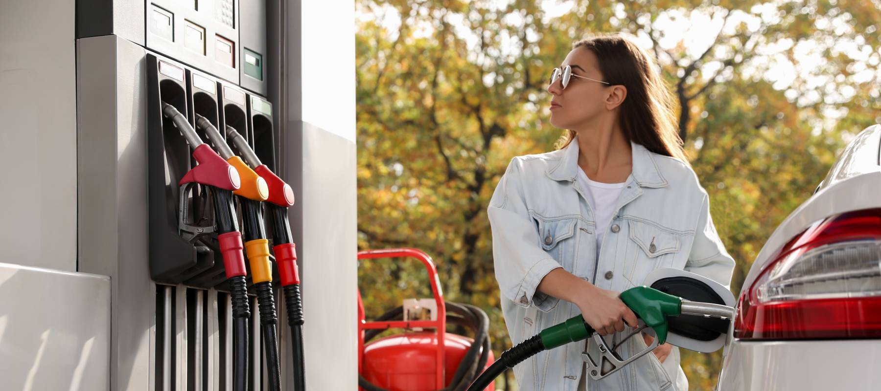 Woman wearing sunglasses filling up her car at the gas station