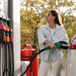 Woman wearing sunglasses filling up her car at the gas station