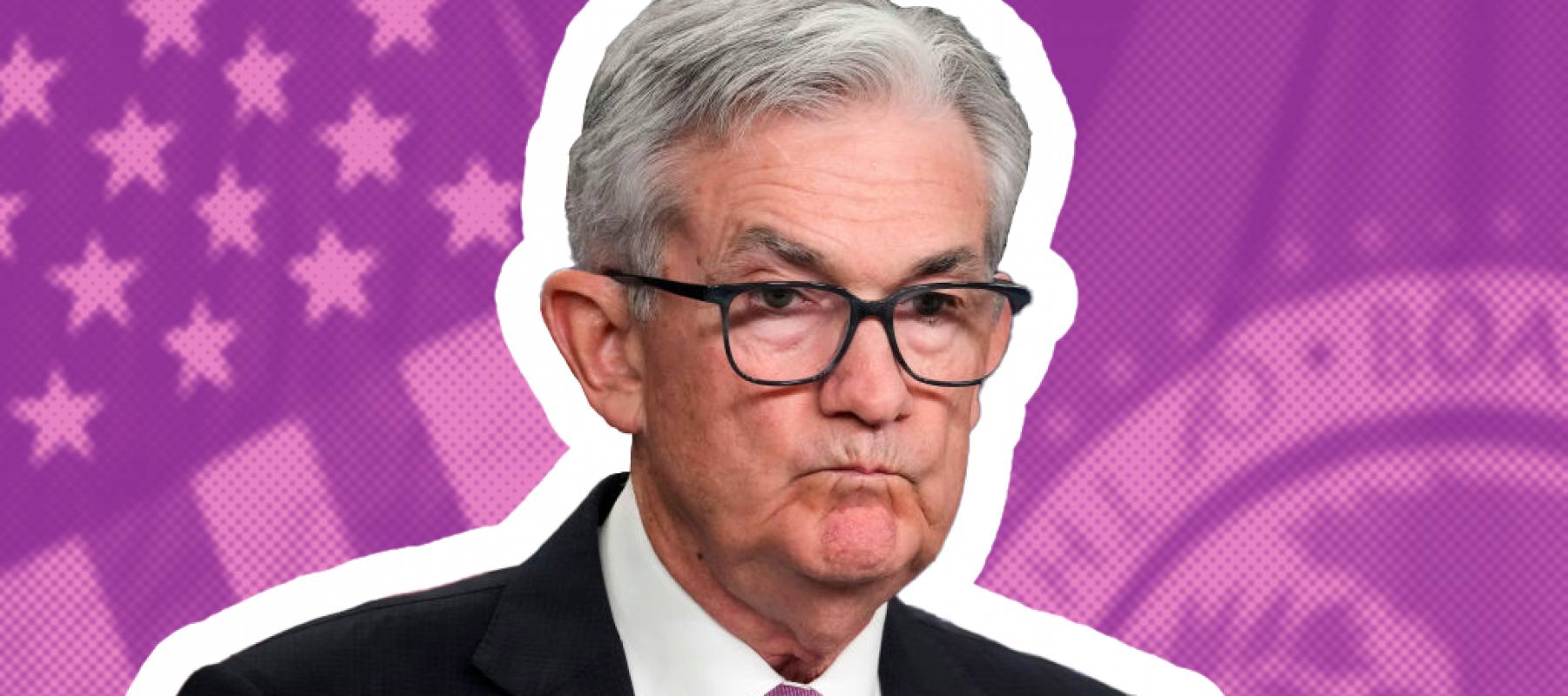 Jerome Powell pulls a sour face sitting in front of an American flag backdrop.