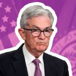 Jerome Powell pulls a sour face sitting in front of an American flag backdrop.