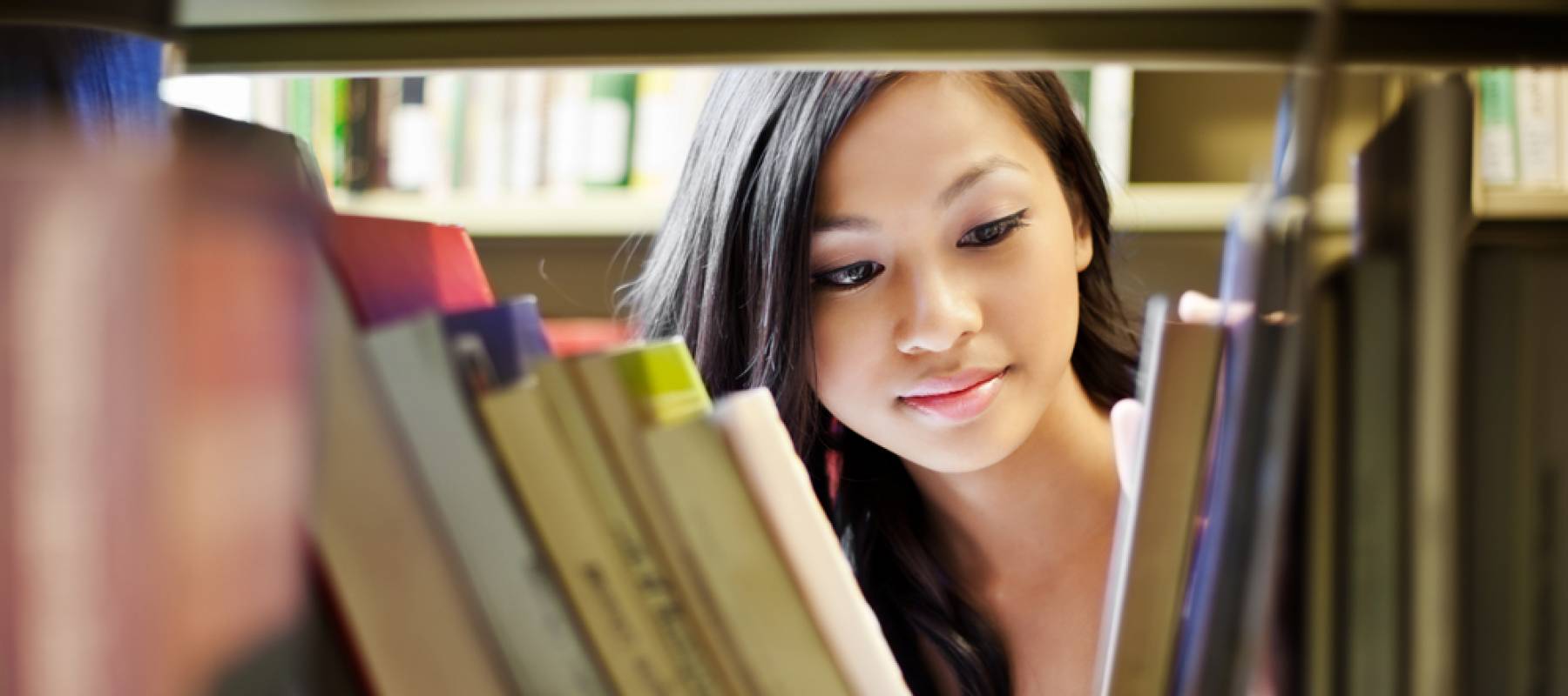Student looks through bookshelf