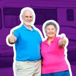 Older couple poses with their thumbs up in front of an RV.