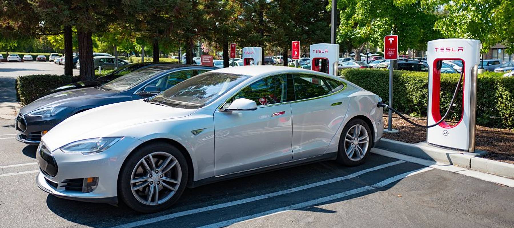 Tesla automobiles plugged in and chargging at a Supercharger rapid battery charging station.