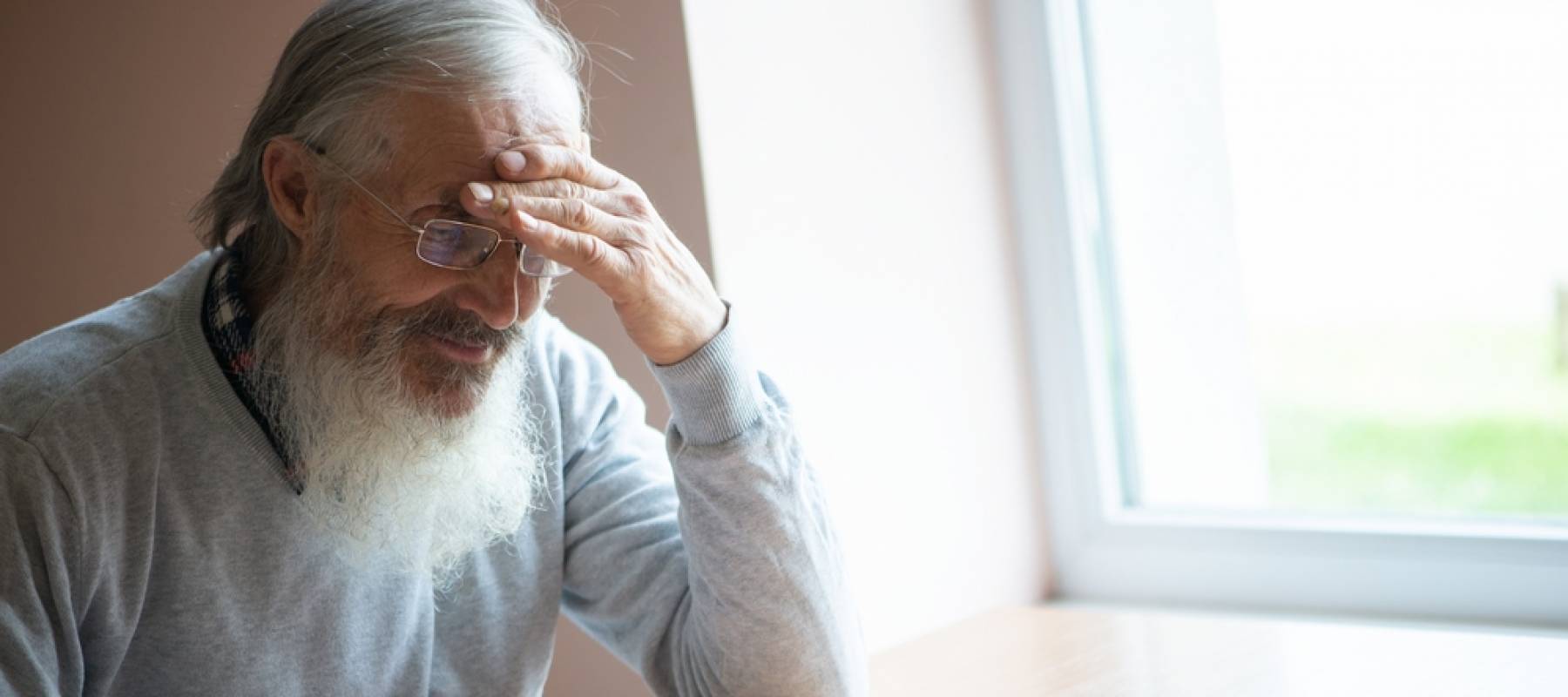 Close up of man looking confused sitting at kitchen table, making notes.