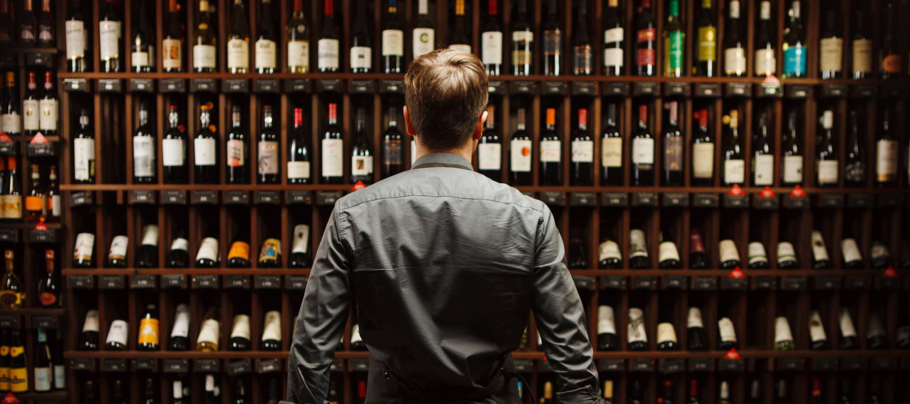 Man standing in front of wine collection
