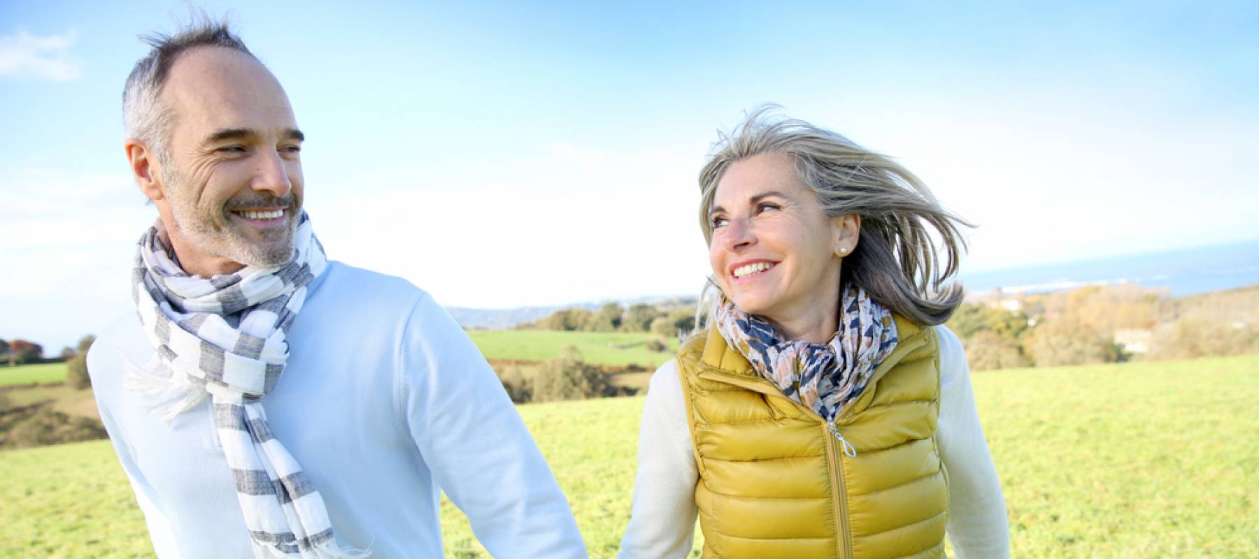 Cheerful senior couple running in countryside.
