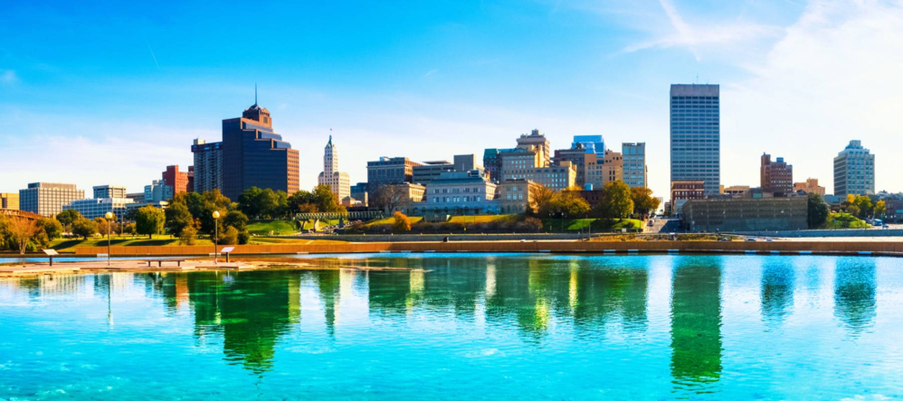 Memphis skyline seen with building reflecting in green-blue water.
