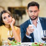 Photo of romantic dinner in expensive hotel. Young woman is bored and lonely while her boyfriend using mobile phone