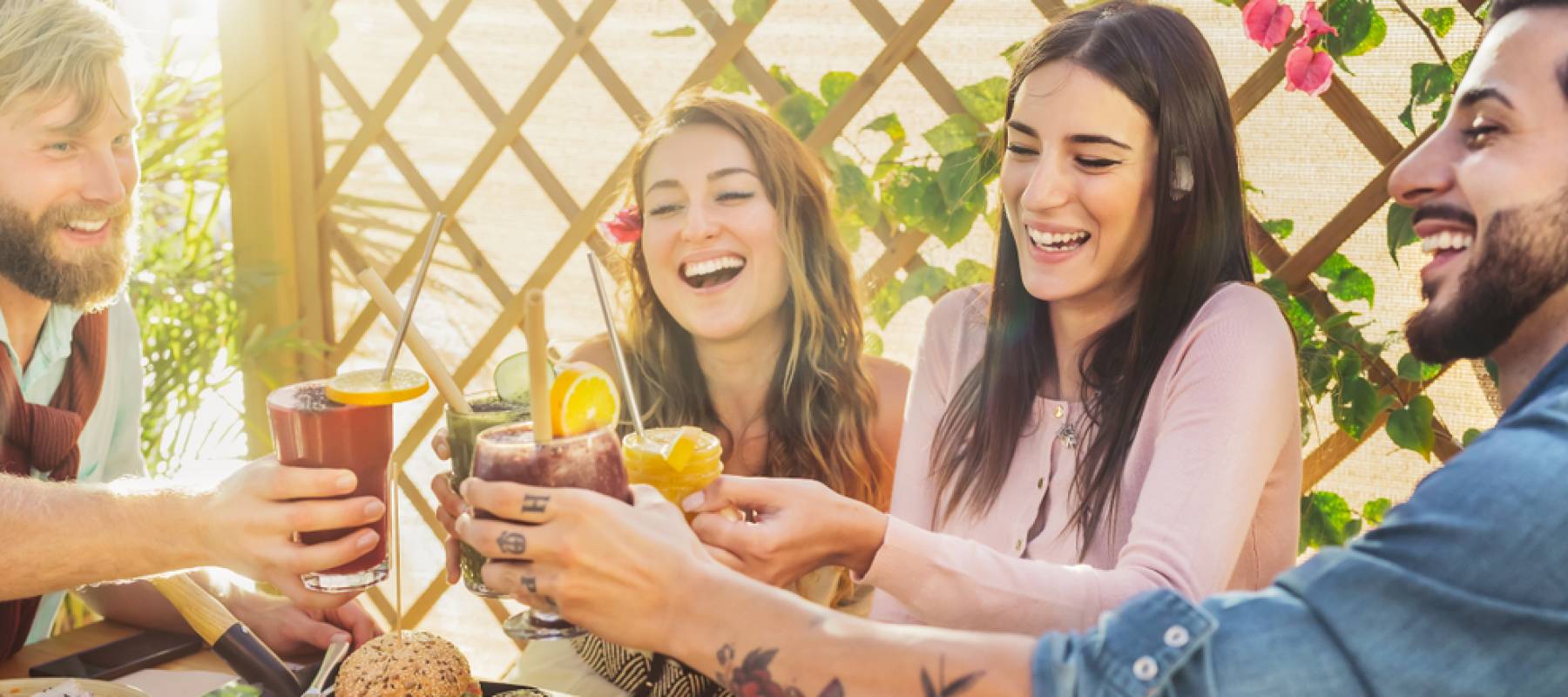 A group of happy young friends clink glasses cheerfully around a table at a restaurant.