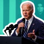 President Joe Biden holds a microphone and makes a pained face while talking.