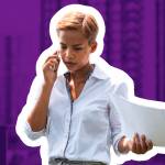 Woman talking on cellphone on balcony of apartment building, looking upset.