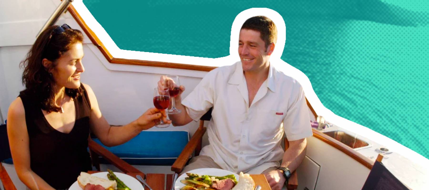 Older couple clink glasses while sitting on a yacht.