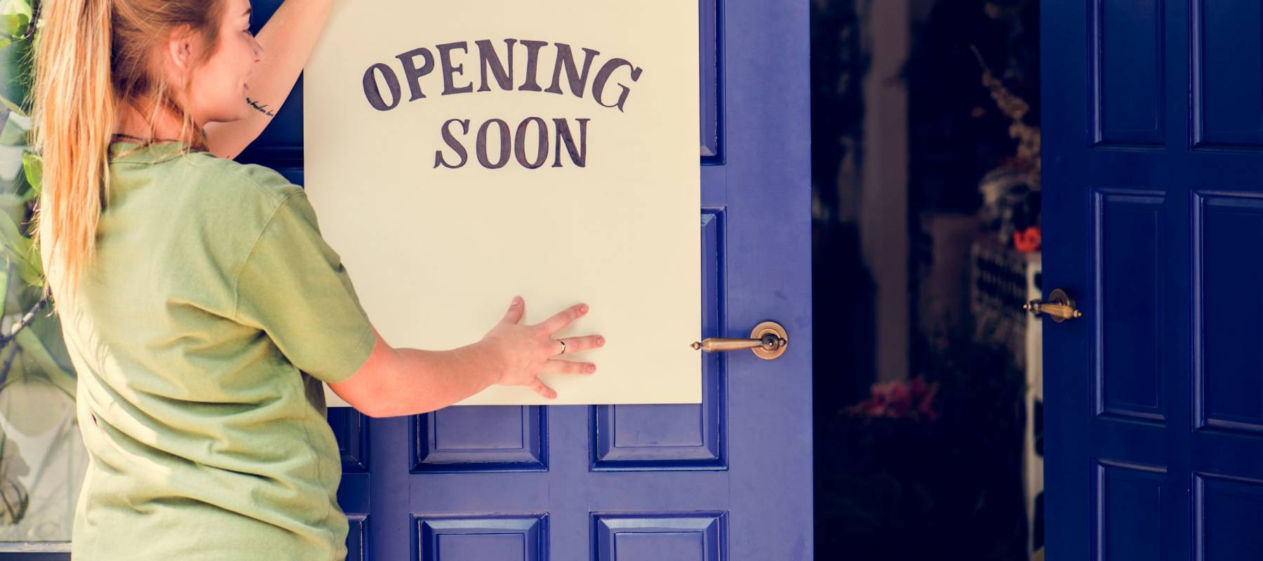 Woman putting on store opening soon sign