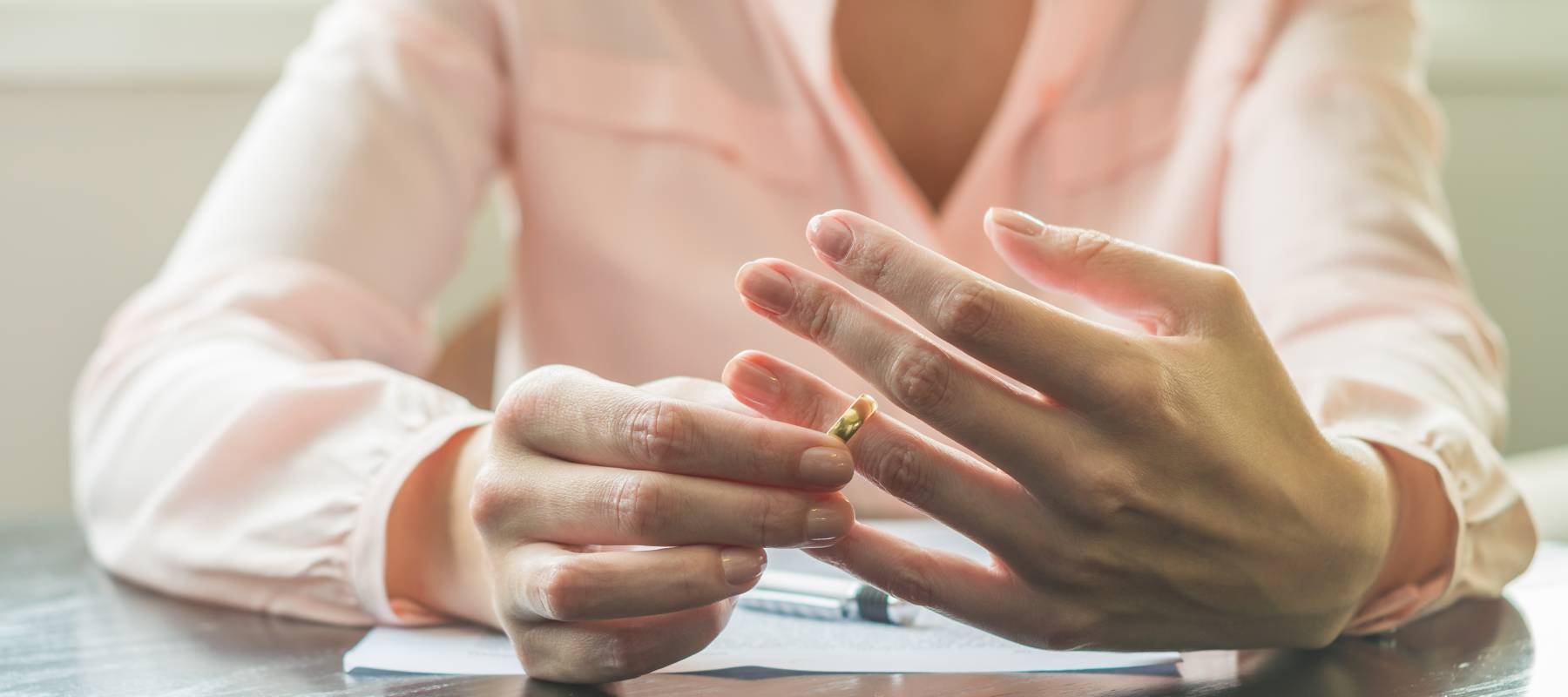 Great concept of divorce, ending of relationship, young woman pulling wedding ring from finger.