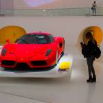 Woman takes photo of luxury red car up close.