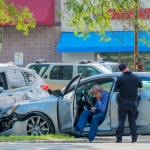 Car accident scene with damaged cars, policeman writing traffic ticket and driver on cell phone.