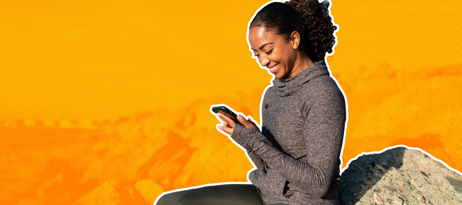 Woman on rocky beach smiling at phone