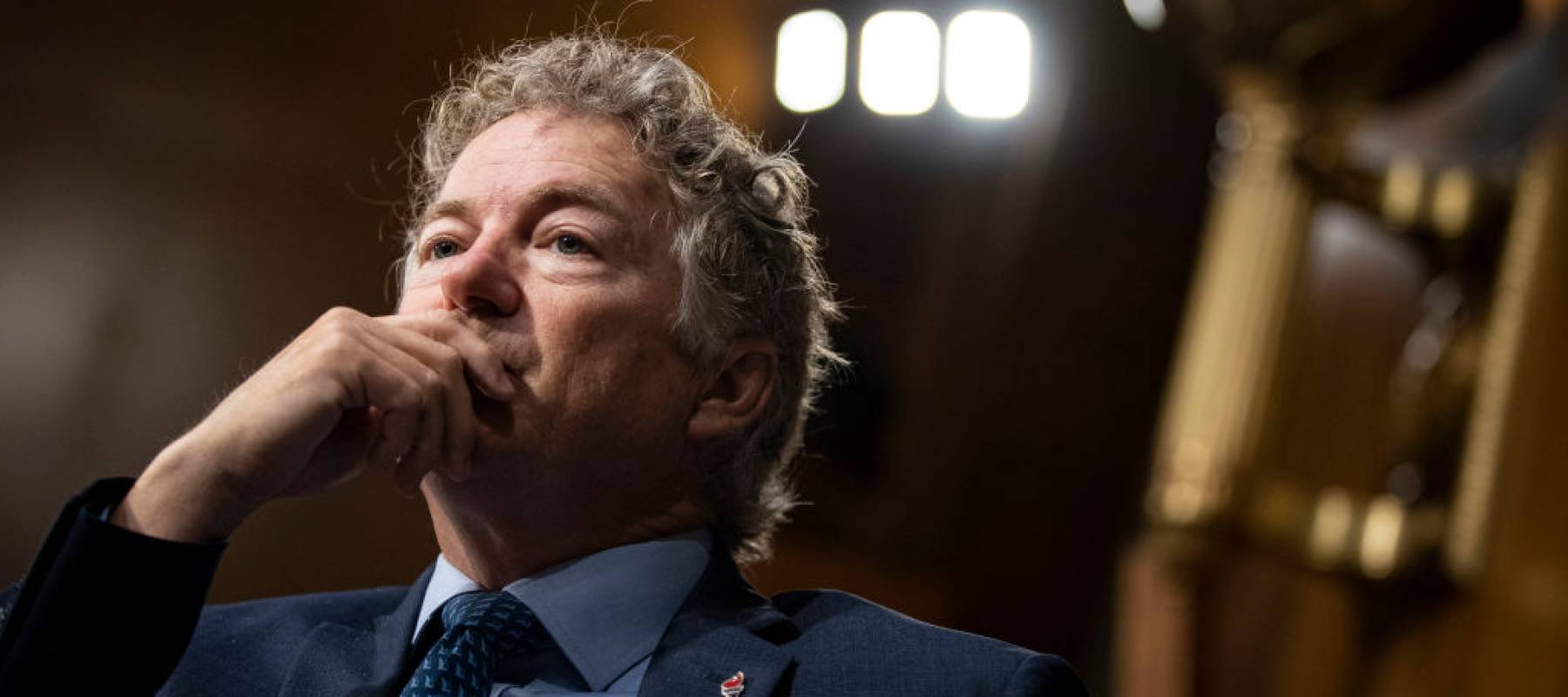 Sen. Ran Paul listens during a Senate Committee meeting with his hand on his chin, looking intent.