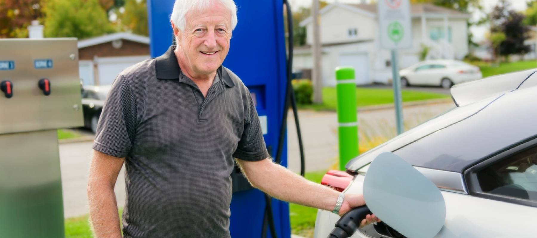 A senior man inserts plug into the electric car charging socket