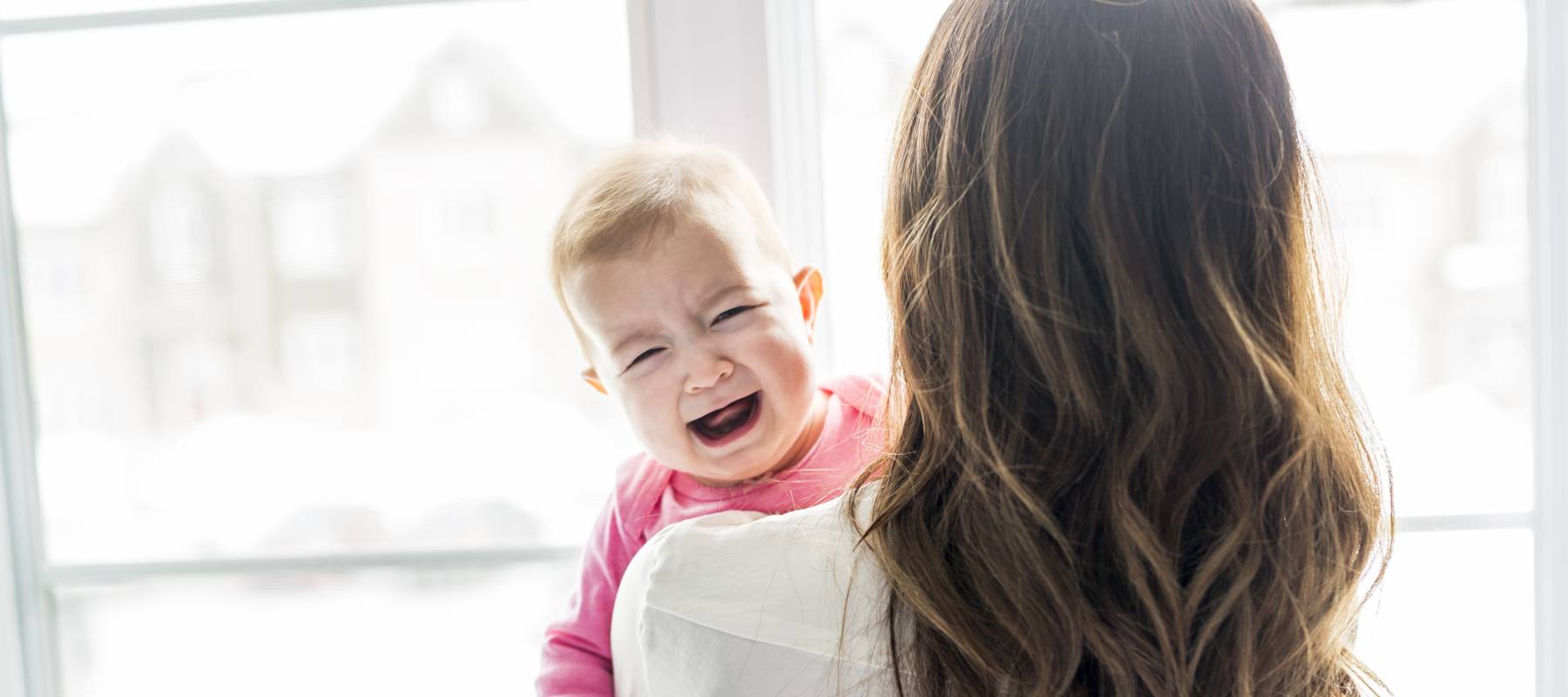 A newborn baby in the hand of his mother at the window
