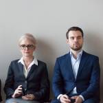 Diverse group of job applicants sitting together outside of an office waiting to be interviewed