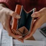 Close-up of woman's hands with empty wallet and utility bills. The concept of rising prices for heating. Many utility bills, coins and hands in a warm sweater holding an open wallet