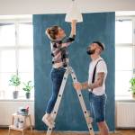 Mid adults couple changing light bulb indoors at home, relocation and diy concept.