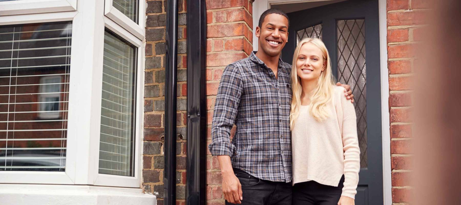 Portrait Of Proud Young Couple Standing Outside First Home Together