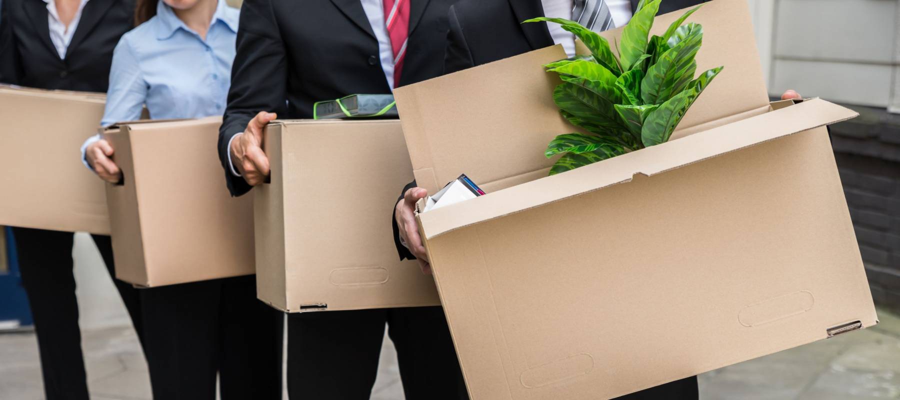 Close-up Of Unemployed Businesspeople Carrying Cardboard Boxes