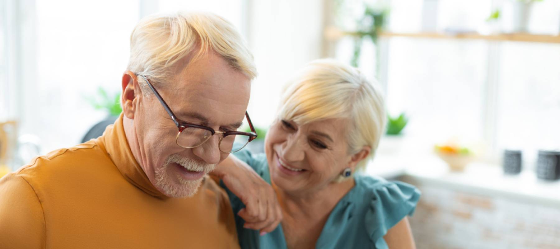 Happy older couple captured candidly in kitchen.