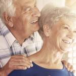 Older couple hugging by a window in their home