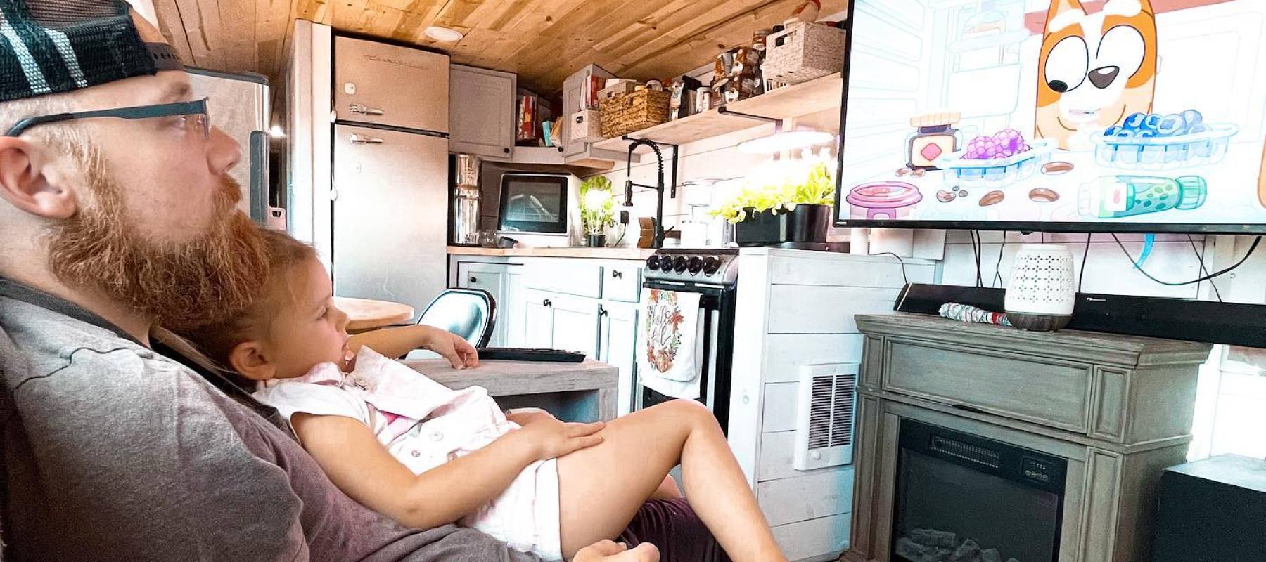 Alex Morris watches TV with his daughter Hadley in their Greyhound bus.